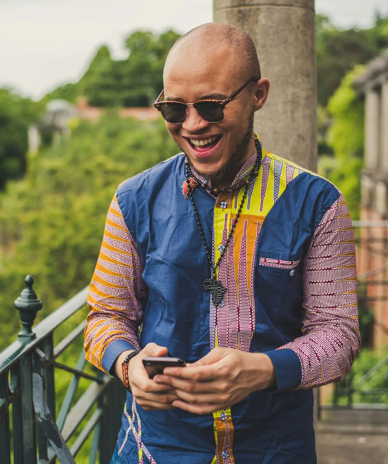 smiling man in multicolored dress shirt and brown sunglasses